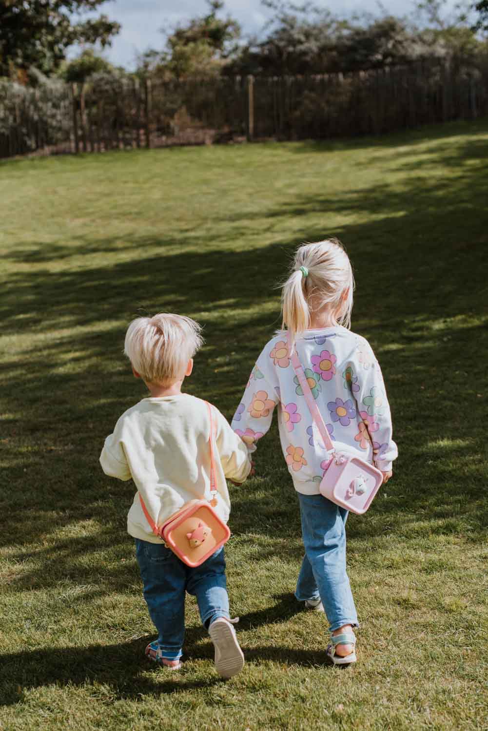 silicon bag unicorn and fox, children are having the bags over its shoulder while walking in the garde, hand in hand