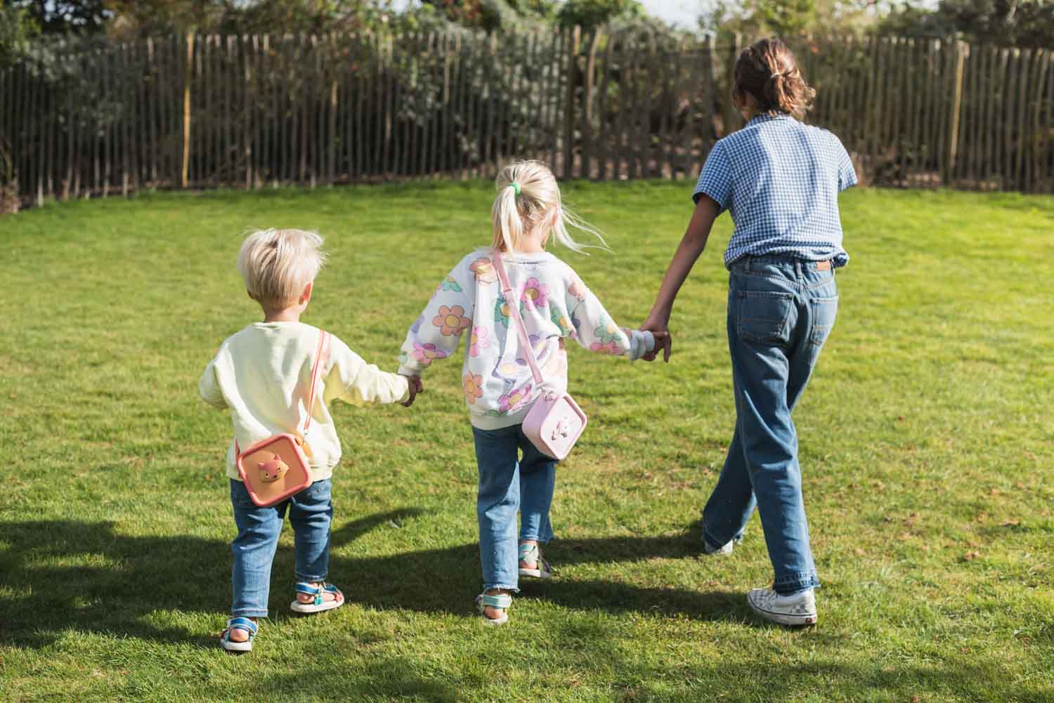 silicon bag fox and unicorn, children are carrying the bag over its shoulder while walking in the garden, hand in hand