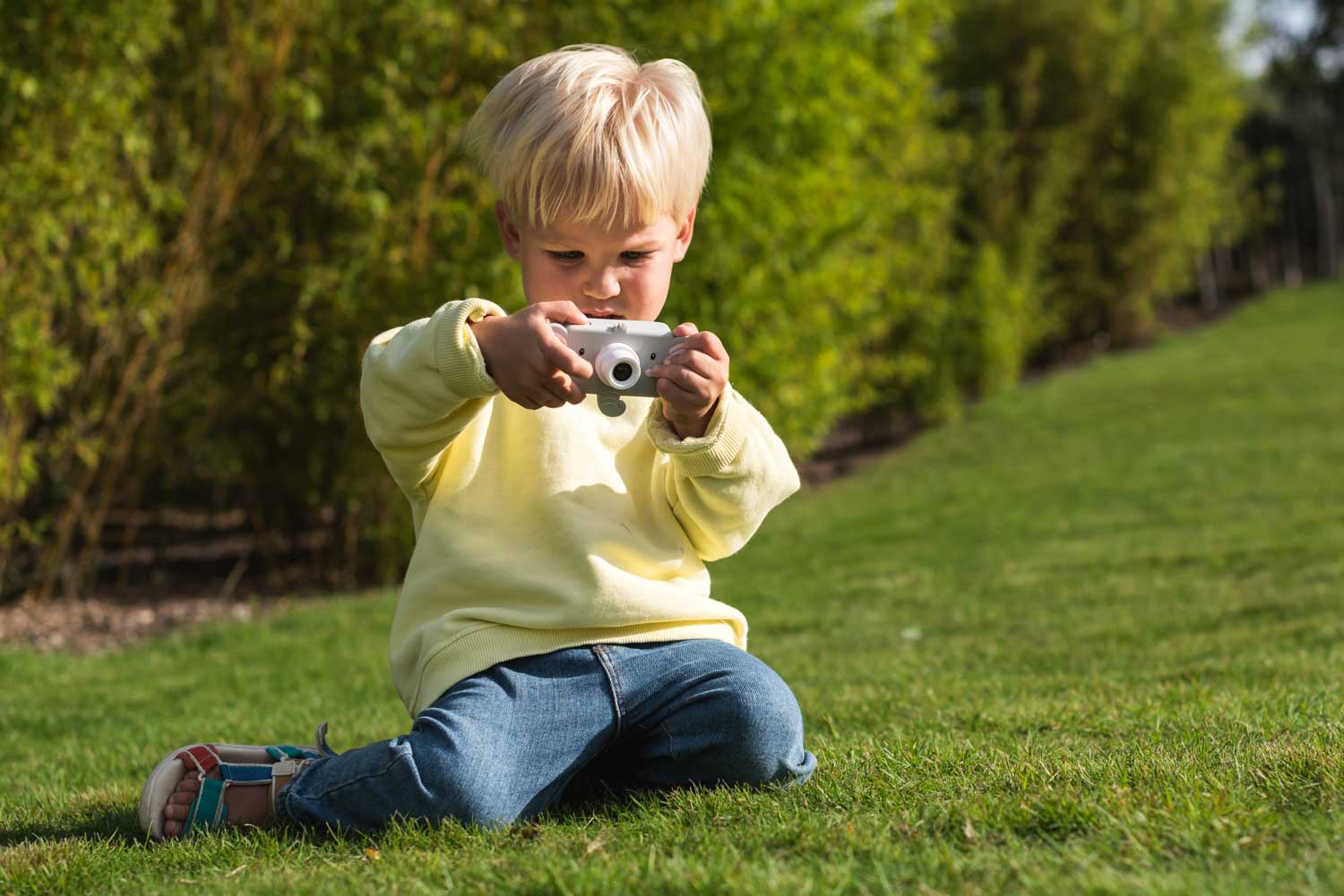 elephant digital kids camera, child is sitting outside while taking pictures