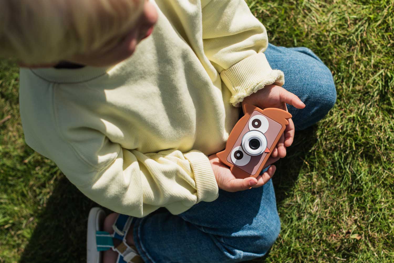 owl digital kids camera, child is sitting outside holding the camera into its hands