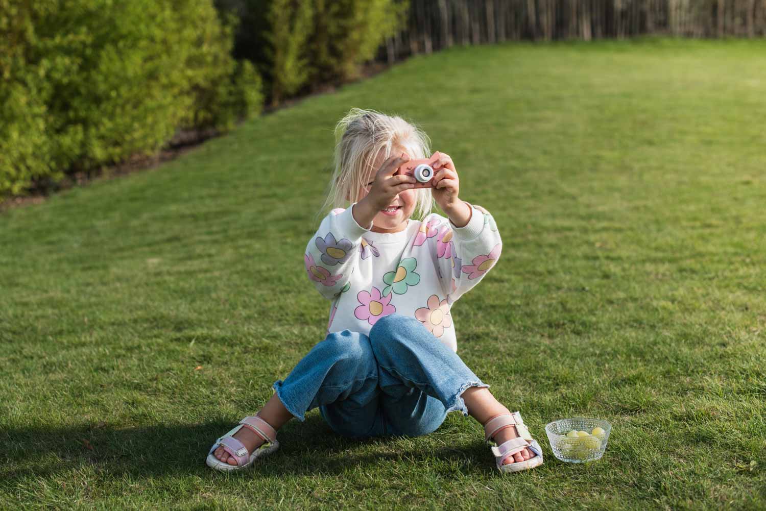 zoo friends cat digital kids camera, child is sitting in the garden and taking pictures while eating grapes