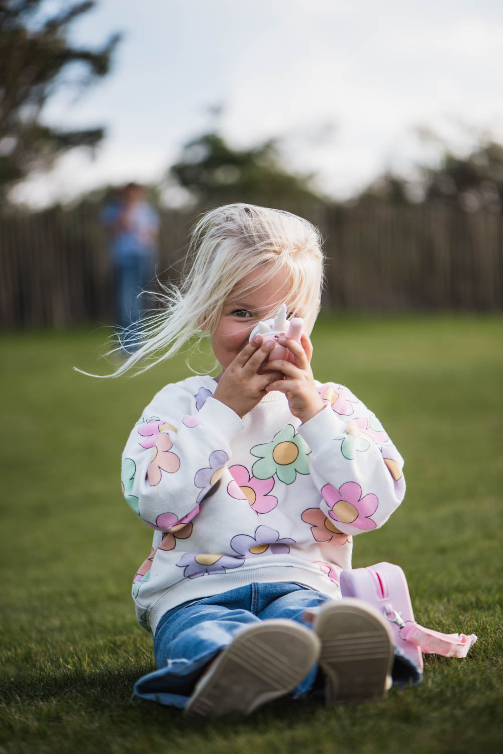 zoo walkie talkie unicorn, child is speaking into the walkie talkie, unicorn bag is next to the child, garden