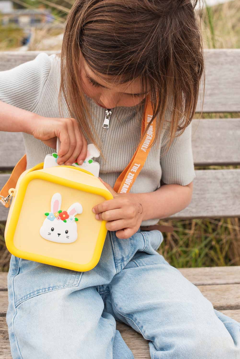 silicon bag rabbit flower, child is carrying the bag over its shoulder while placing the rabbit camera into the bag