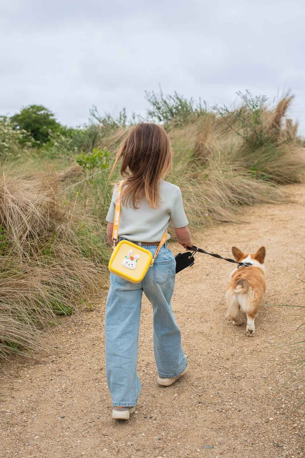 silicon bag rabbit flower, child is carrying the bag over its shoulder while walking at the beach with a dog