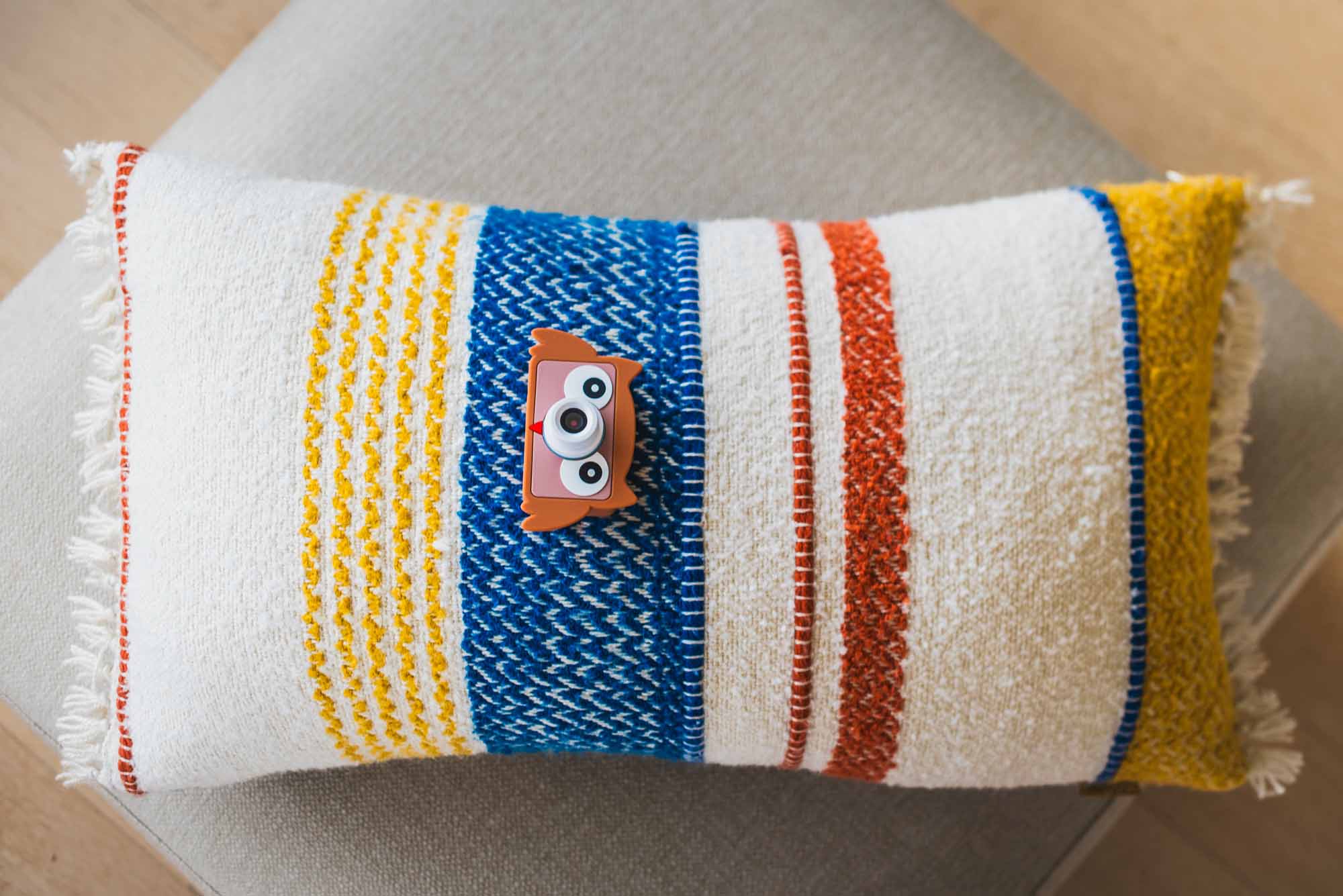 blue digital kids camera with owl sleeve, camera is lying on a pillow