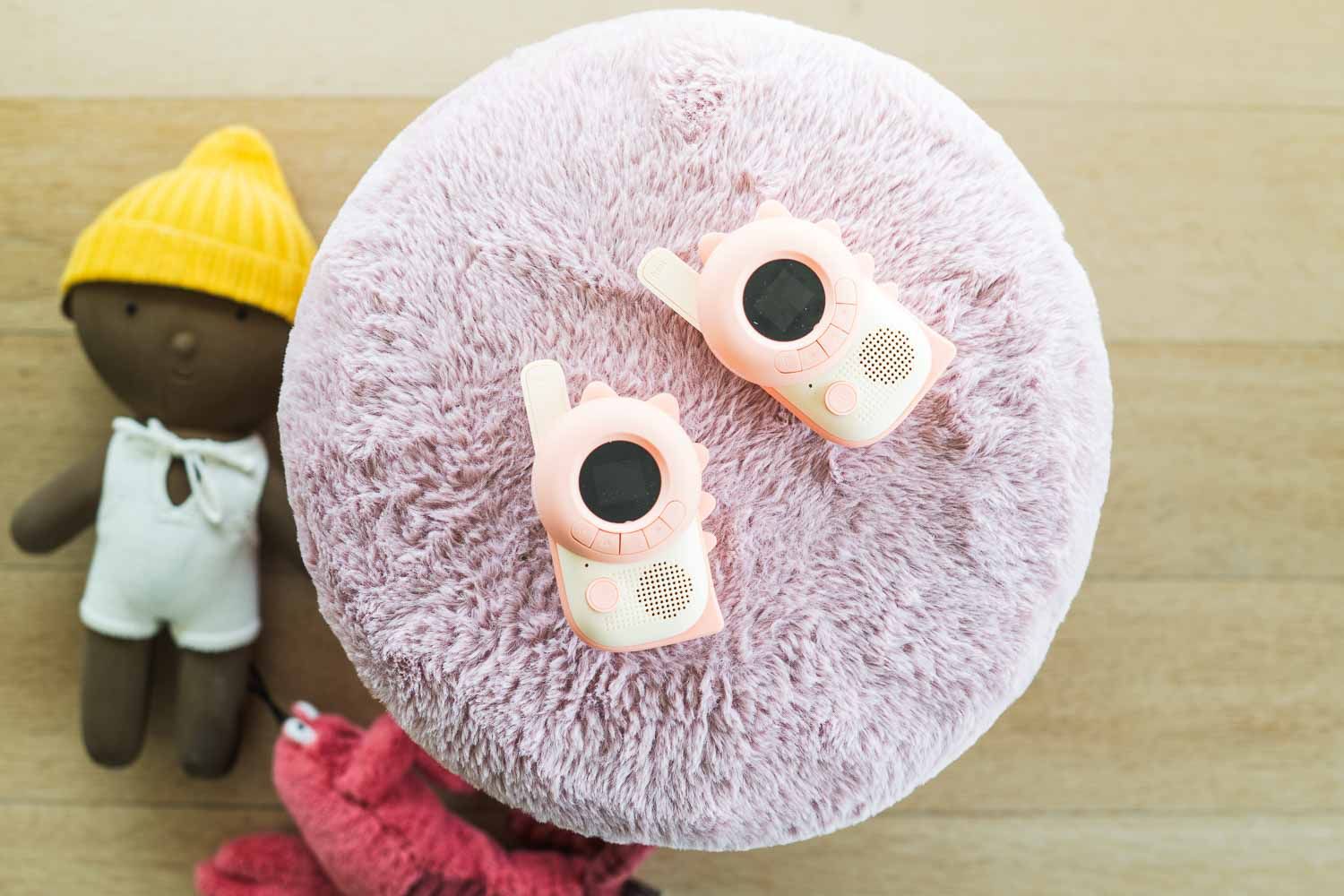 zoo walkie talkie set dino pink, lying on a pillow with cuddles aside