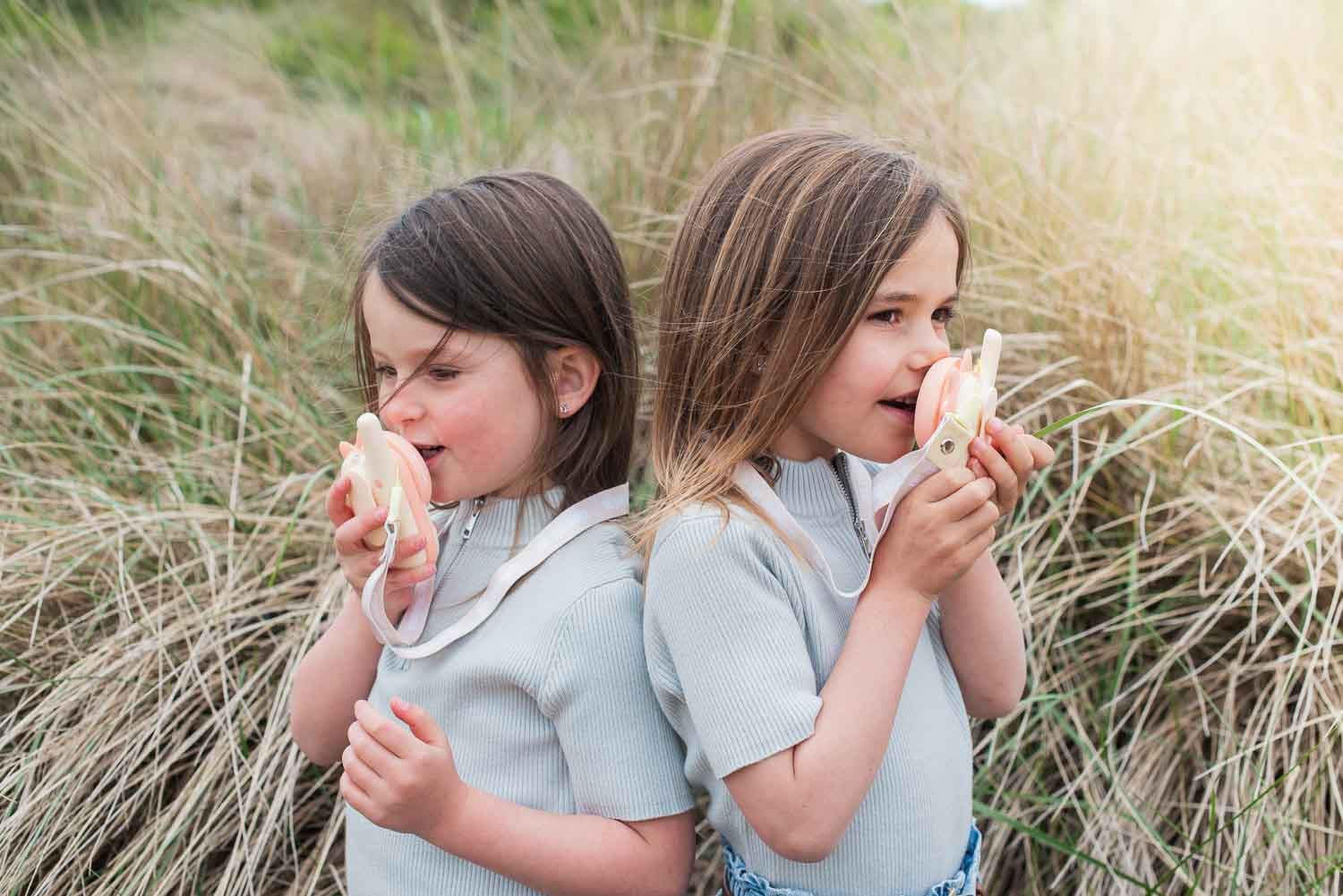 zoo walkie talkie set dino pink, children are standing between the dune grass, playing with the walkie talkies