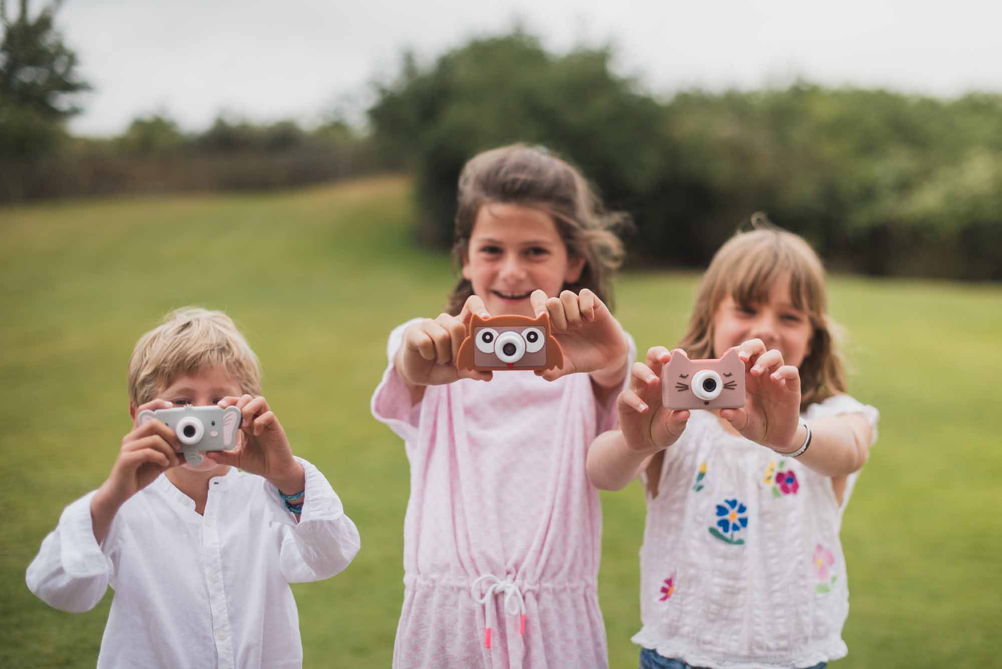mix of owl, cat and elefant kids digital cameras, kids are standing in the garde, showing the cameras
