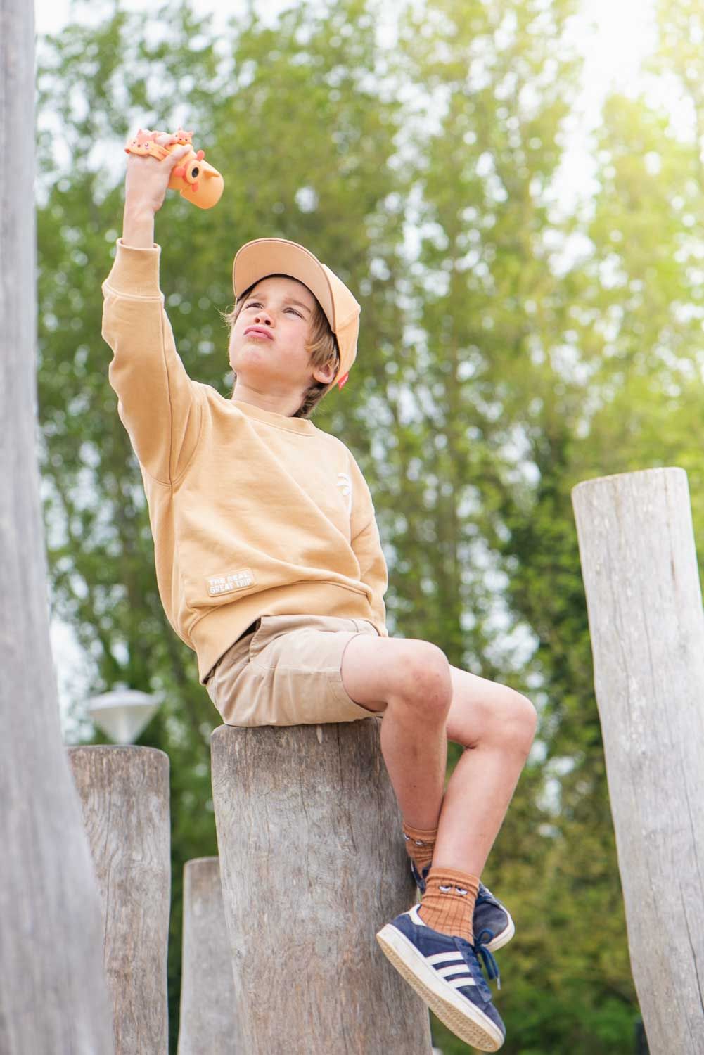 zoo video fox digital kids camera, child is sitting on a tree trunk while playing with the video camera