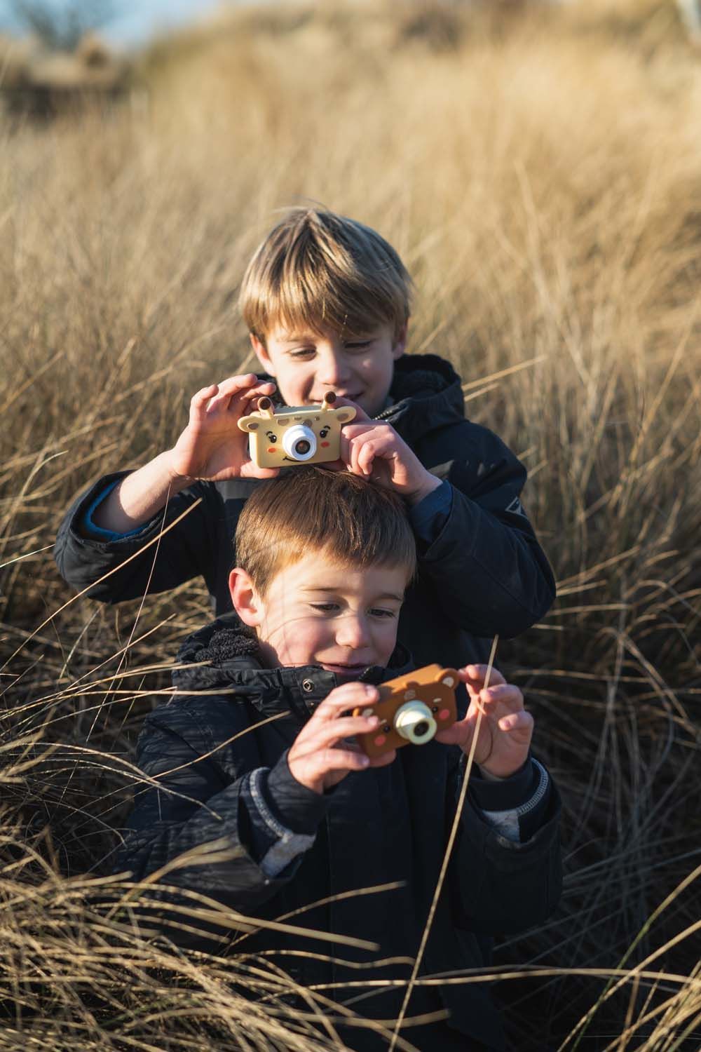 zoo friends giraffe and bear digital kids camera, children are sitting in the beach grass while taking pictures