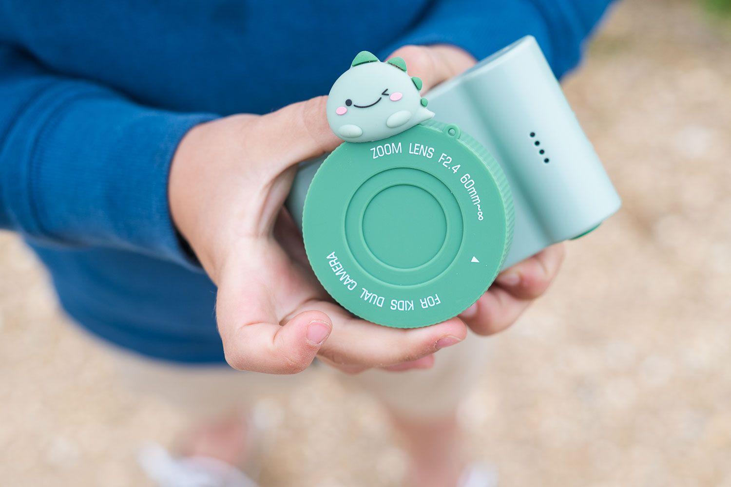 urban zoo dino green digital kids camera, child is holding the camera with the lenscover in its hands