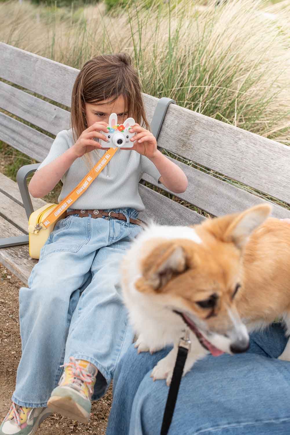zoo friends rabbit flower digital kids camera, child is sitting on a banc while taking a picture of a dog