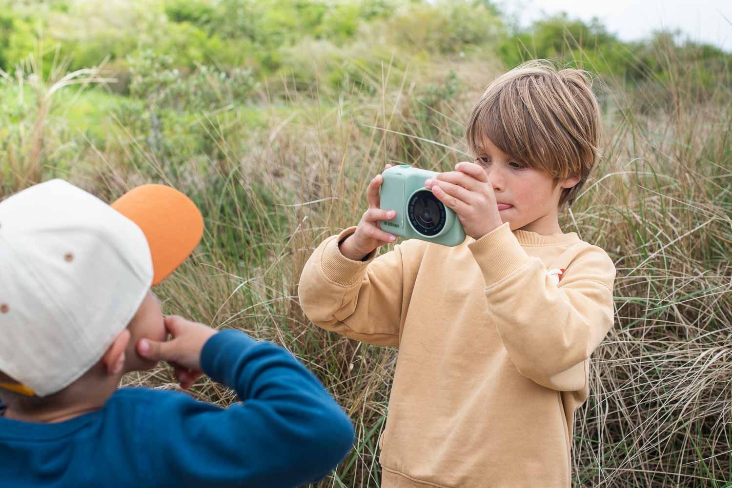 zoo print dino green digital kids camera, child is taking a picture of a friend who's making a funny face