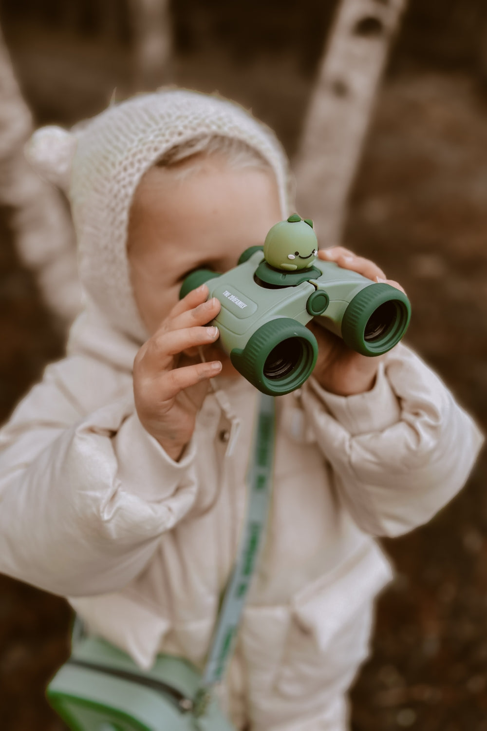 A girl is looking through binoculars at something nearby.