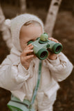 odalA girl is looking through binoculars at something nearby.