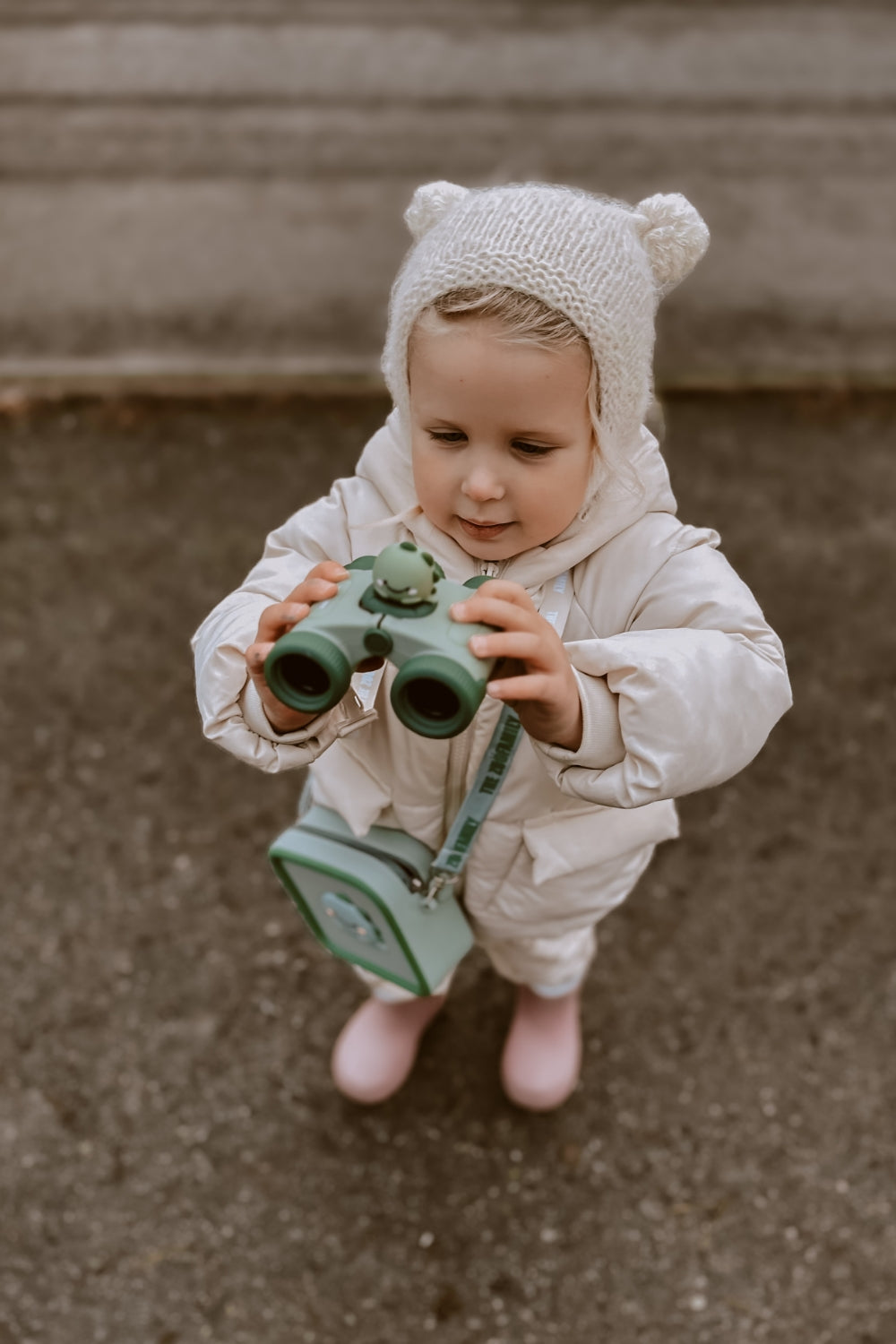 A girl is looking at the binoculars with interest.