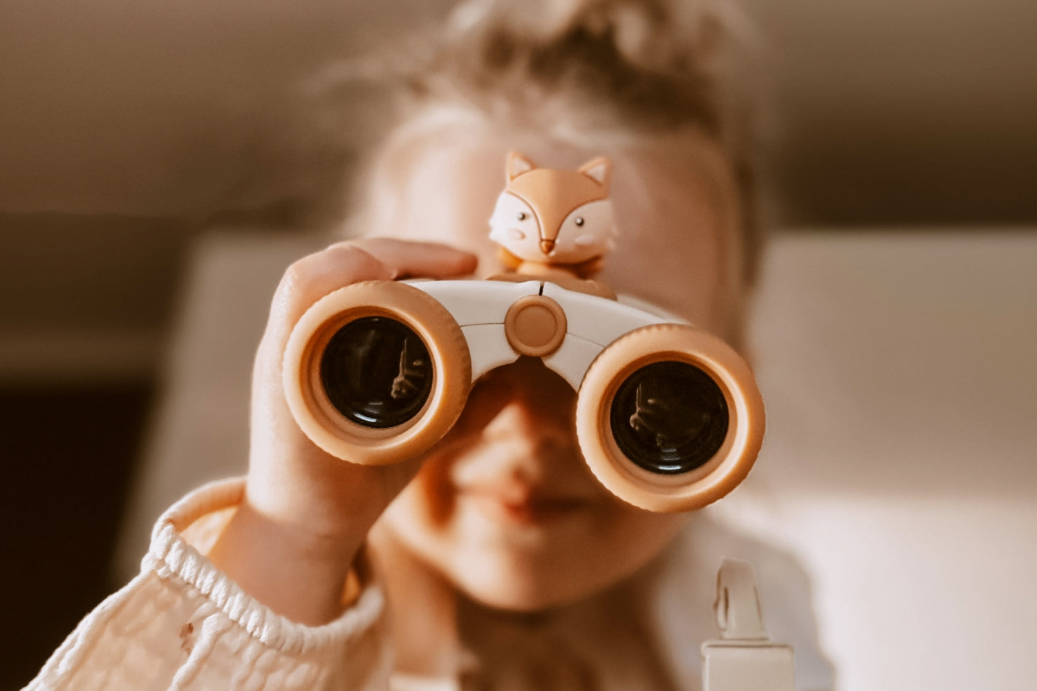 A girl is looking at an object through her binoculars.