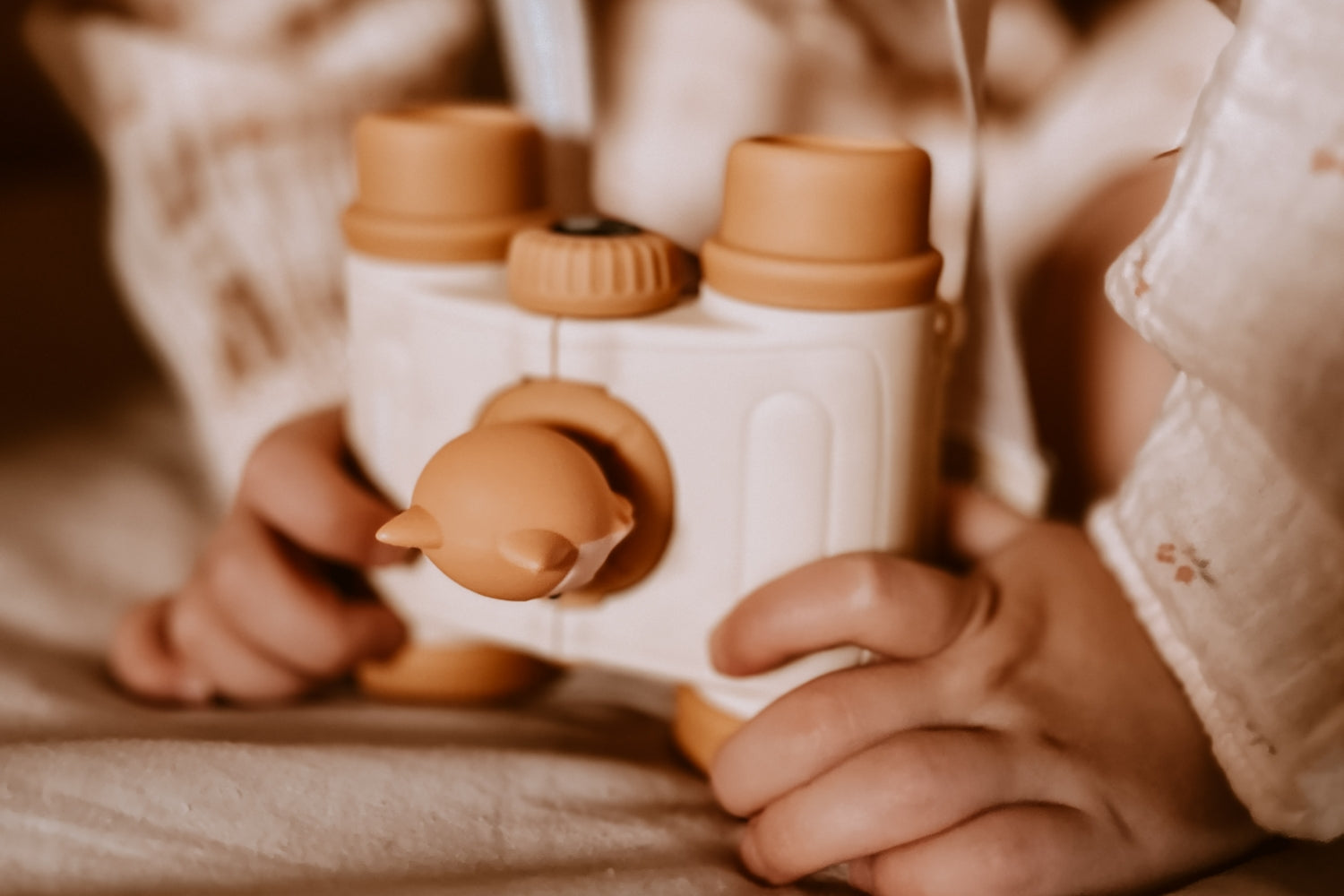 The girl is putting the binoculars on the playmat.