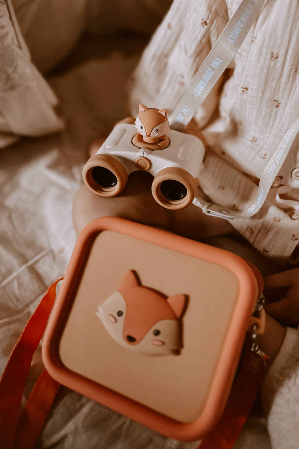 A girl is playing with her binoculars and a silicone bag in her hands.