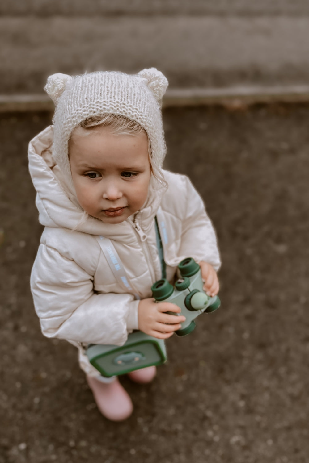 A girl is looking into the distance, holding binoculars.