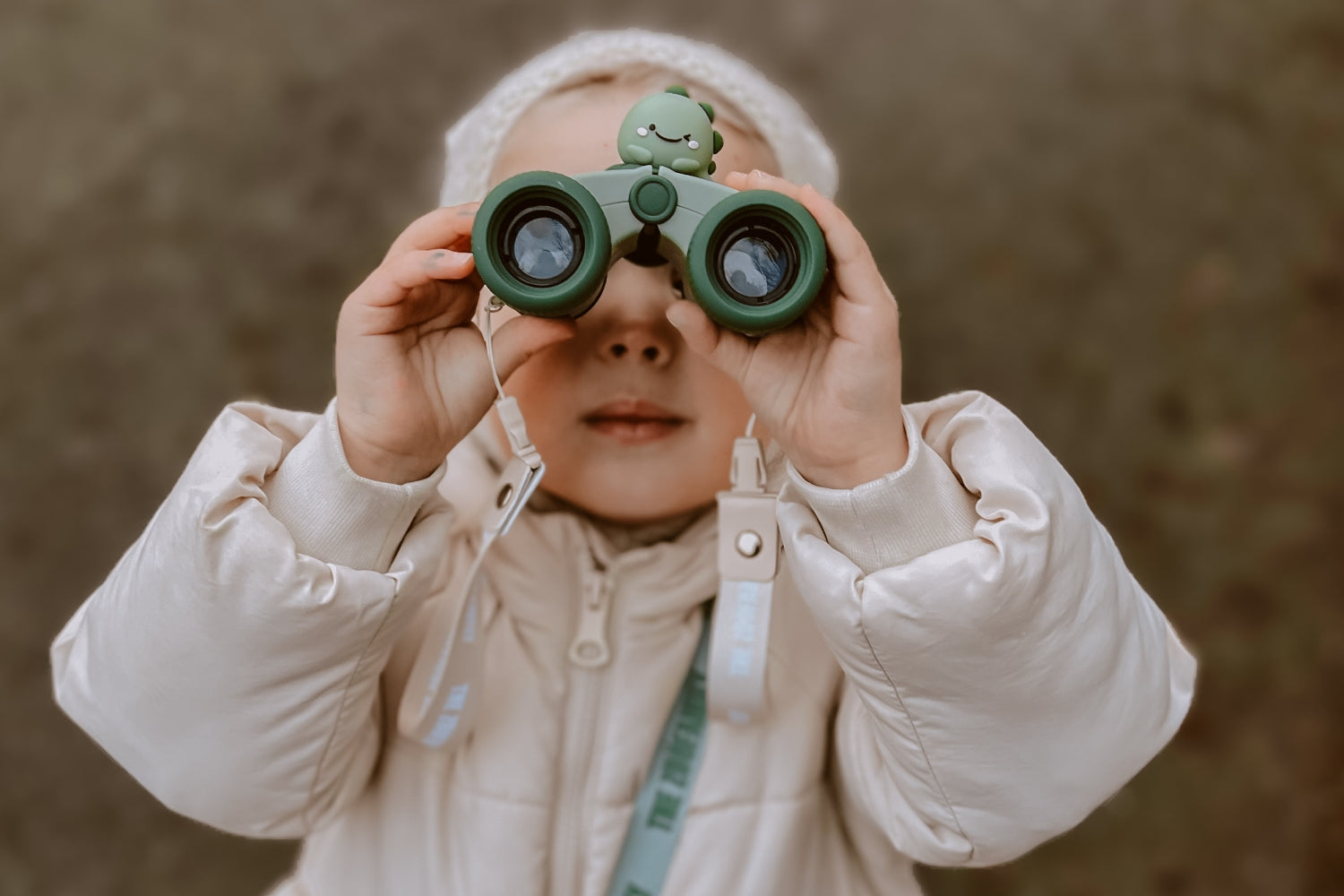 A girl carefully examines the surrounding view through her binoculars.