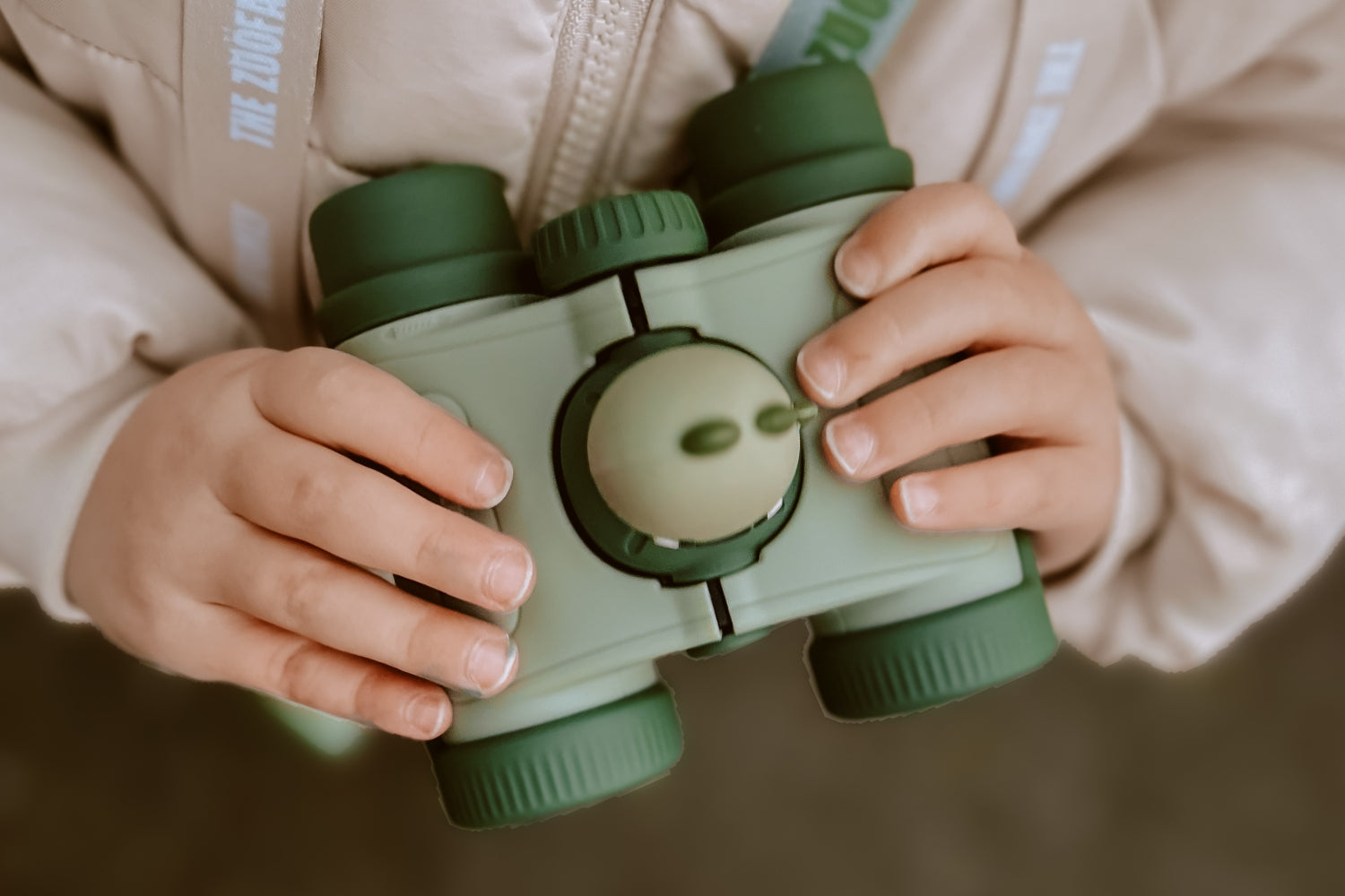 A girl holds the binoculars with both hands.