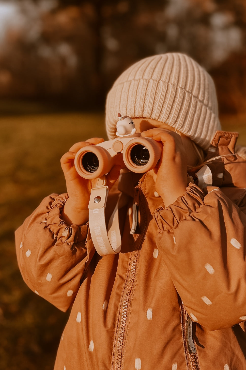 A girl is looking into the distance through her binoculars.