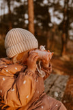 odalA girl is sitting in the forest, carefully looking around through binoculars.