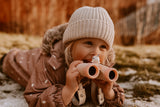 odalThe girl is lying on the ground, smiling and looking through her binoculars.
