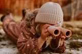 odalThe girl is lying on the barely snow-covered grass, propped up on her elbows, looking through binoculars.