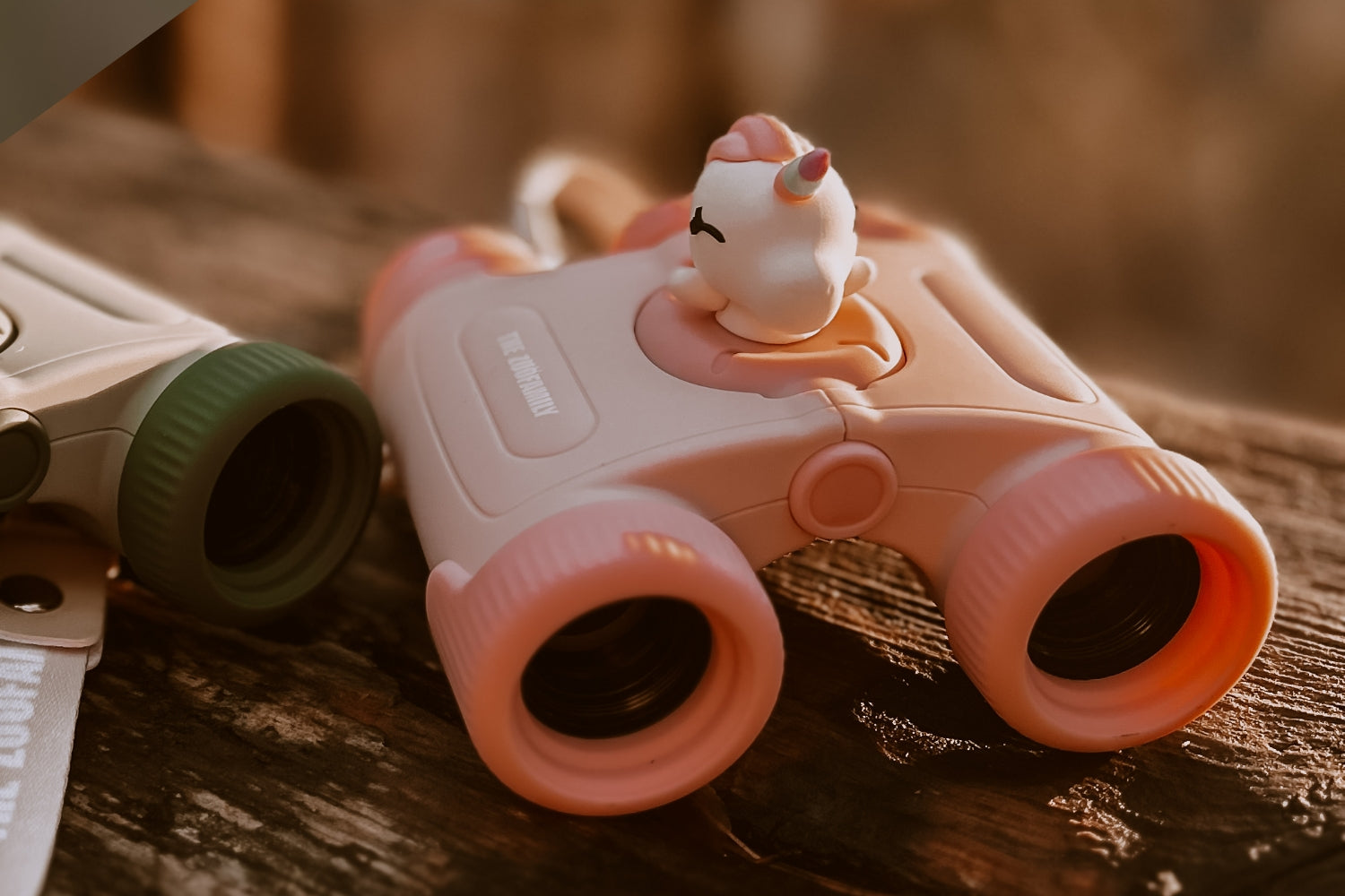 A pair of binoculars is lying on a wooden surface.