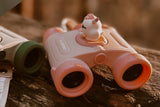 odalA pair of binoculars is lying on a wooden surface.