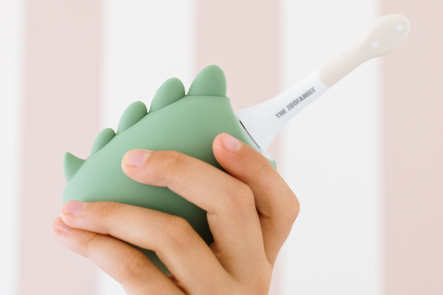 A hand holding the Dino toothbrush.