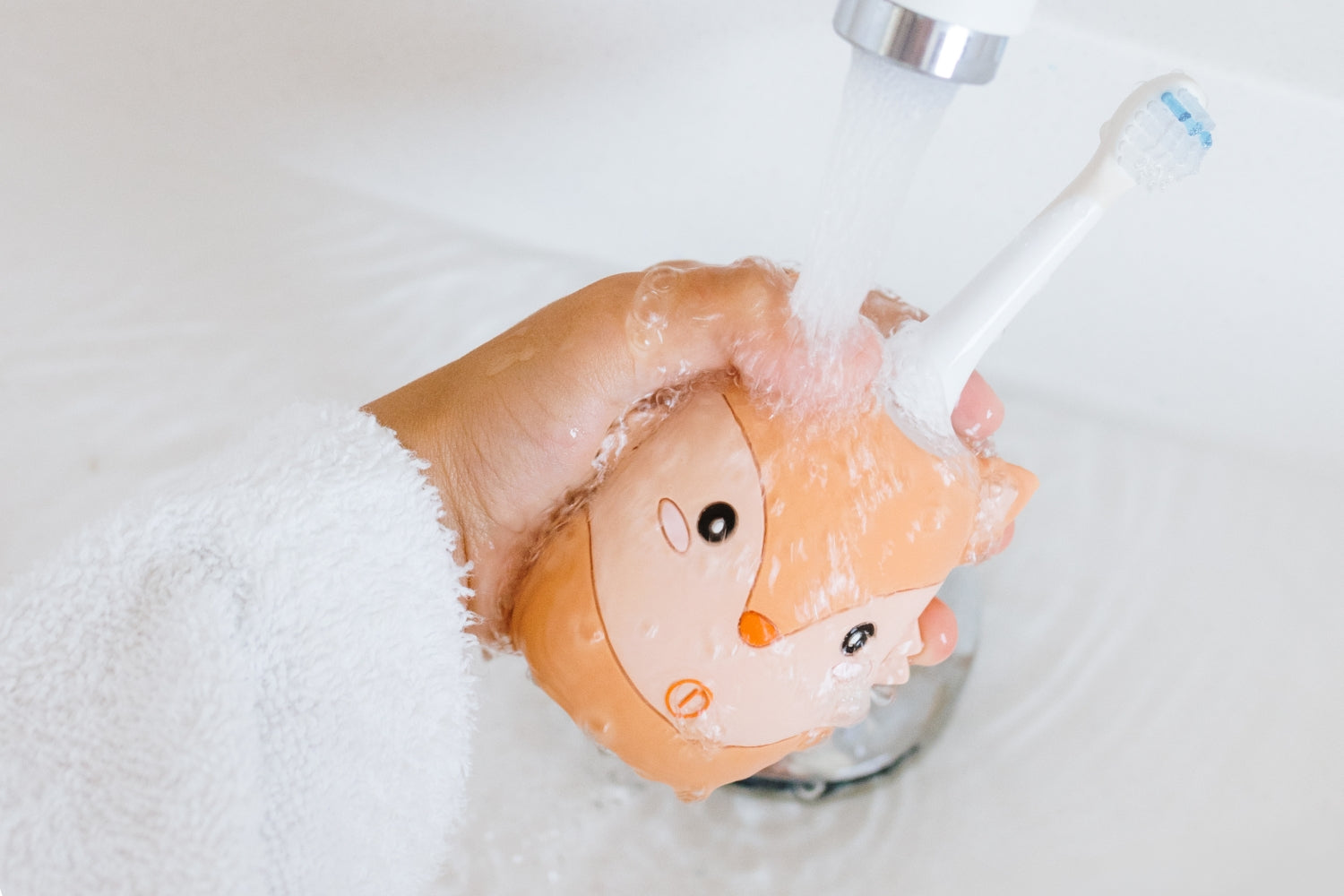 A hand holds the Fox toothbrush while cleaning it under running water