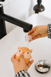 odalA hand holds the Fox toothbrush while cleaning the brush head under running water.