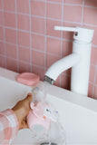 odalA pink unicorn-shaped toothbrush being rinsed under running water.