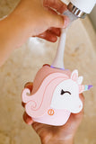 odalA pink unicorn-shaped toothbrush  handheld device being used under running water, held in a person's hands.