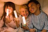 odalThree children holding Zoo Light lamps under a blanket.