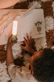 odalA child reading a book with a Zoo Light Dino on a textured surface.