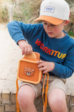 odalzoo print bear digital kids camera, child is sitting at the beach, placing the camera into the silicon bear bag