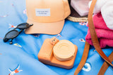 odalzoo print bear digital kids camera, laying on a outdoor beach bag of Play&Go, towels, a hat and sunglasses
