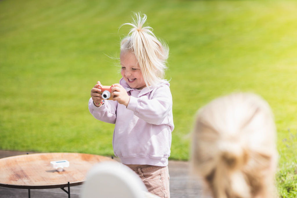 fox kids camera, child holding camera with both hands, laughing and playing in garden 