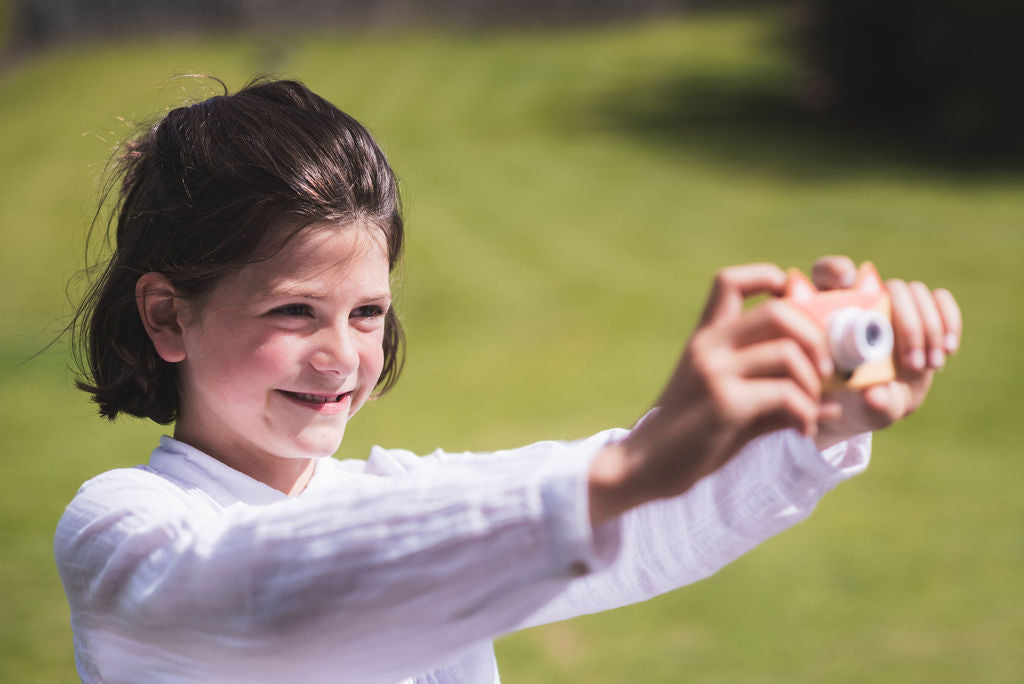 fox kids camera, child holding camera with both hands, laughing while making a picture